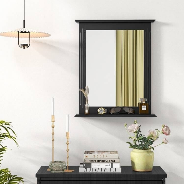 Black-framed mirror on a white wall with decorative items below.