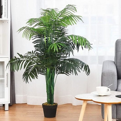 Artificial palm plant in a living room setting with a coffee table and chair.