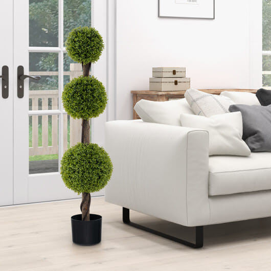 Living room with a white sofa, decorative topiary plant, and a window.