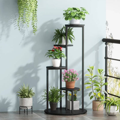 Black metal plant stand with various potted plants against a light blue wall.