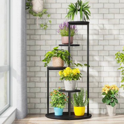 Black metal plant stand with various potted plants against a tiled wall.