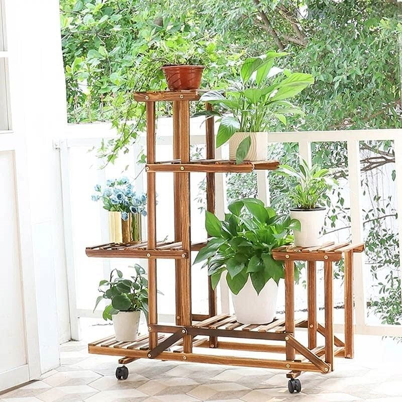 Wooden plant stand with multiple shelves holding various potted plants in a bright indoor setting.