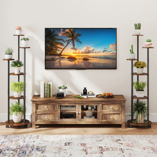 Wooden TV stand with a television displaying a beach scene, flanked by decorative shelves with plants.