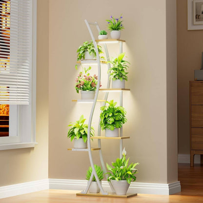 Tall, multi-tiered plant stand with various potted plants against a beige wall.