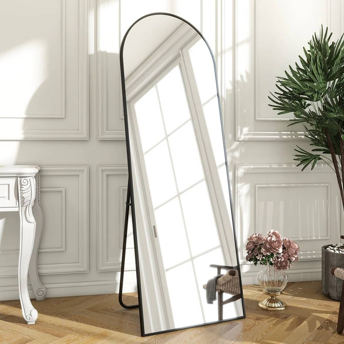 Full-length mirror in a room with white walls and wooden floor.