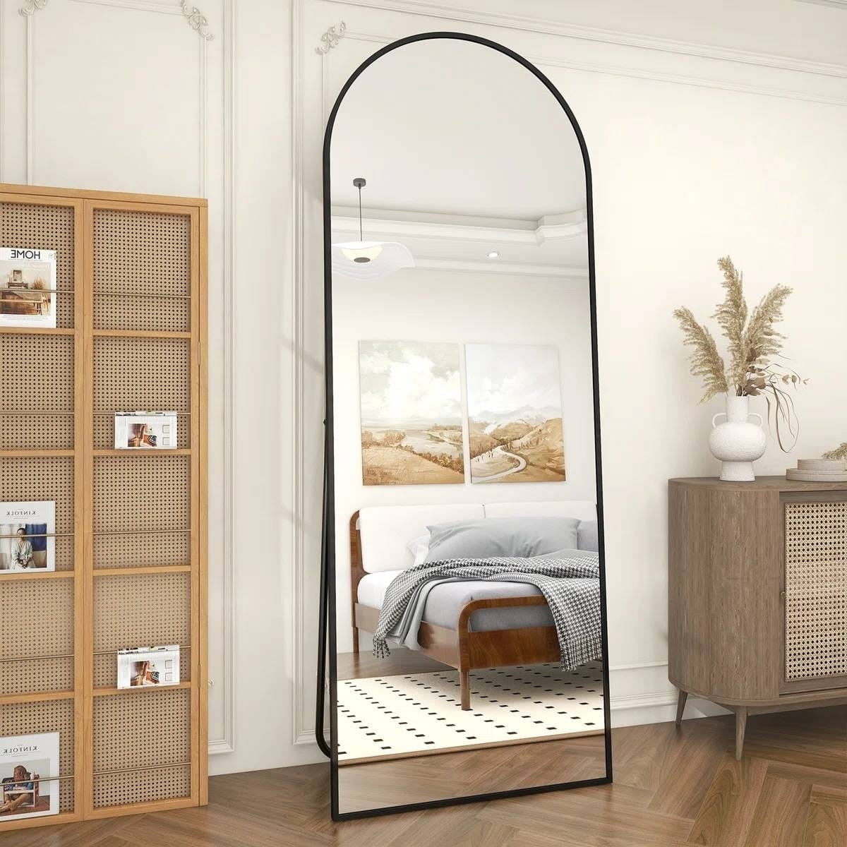 Full-length mirror leaning against a wall in a room with wooden furniture and decor.