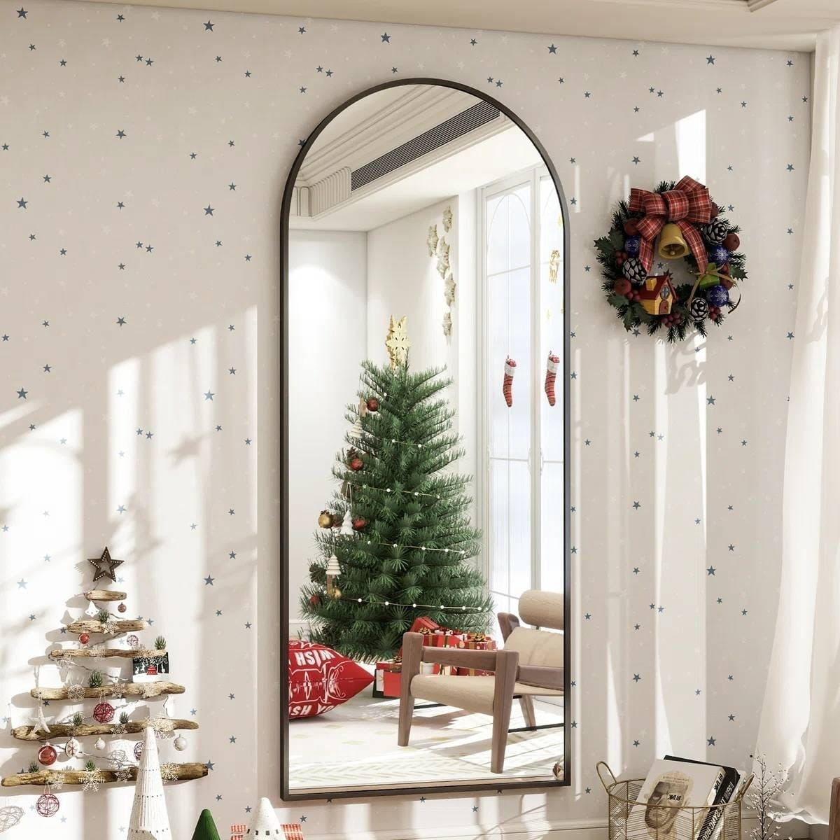 Decorative mirror with Christmas tree reflection in a room with festive decorations.