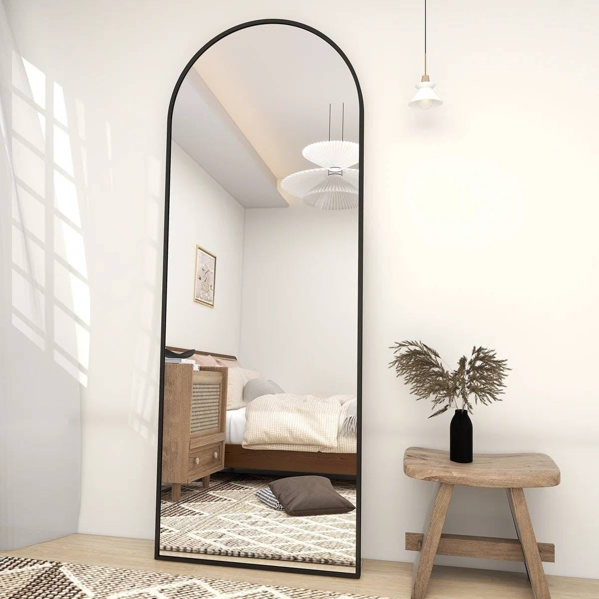 Full-length mirror in a bedroom with wooden stool and plant