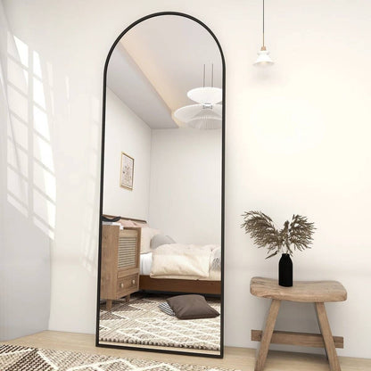 Full-length mirror in a bedroom with wooden stool and plant