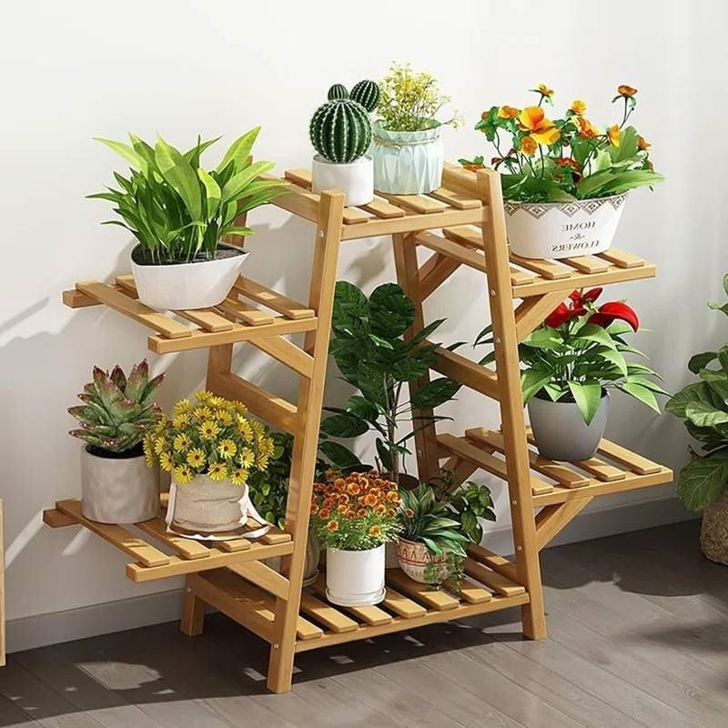 Wooden plant stand with various potted plants on a wooden floor.