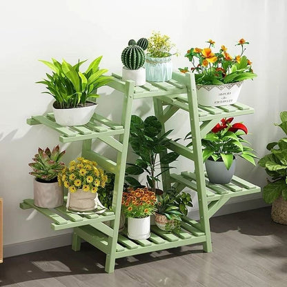 Green plant stand with various potted plants against a white wall.