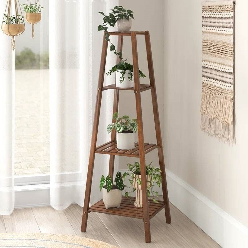Wooden plant stand with potted plants in a room with a window and wall art.