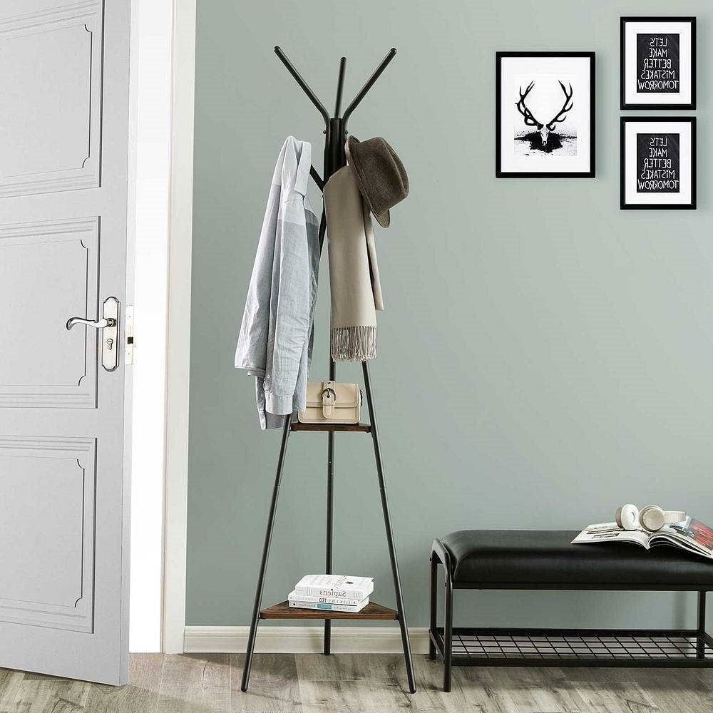 Coat rack with clothes against a light gray wall with framed pictures.