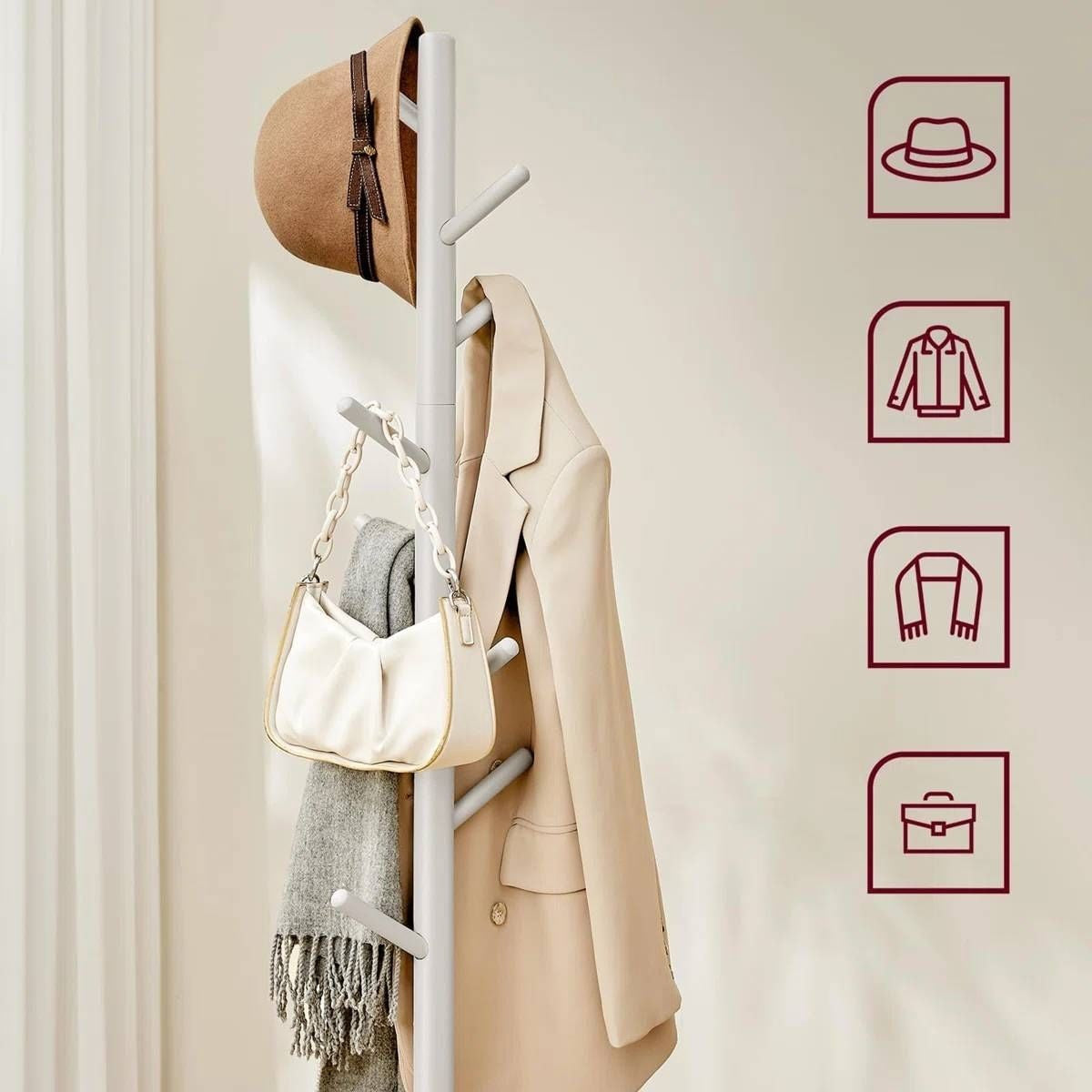 White coat rack with a beige coat, white bag, and brown hat against a light background.