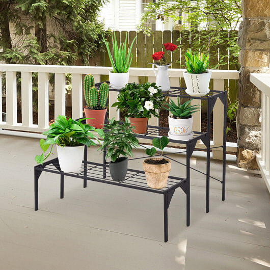 Black metal plant stand with various potted plants on a deck