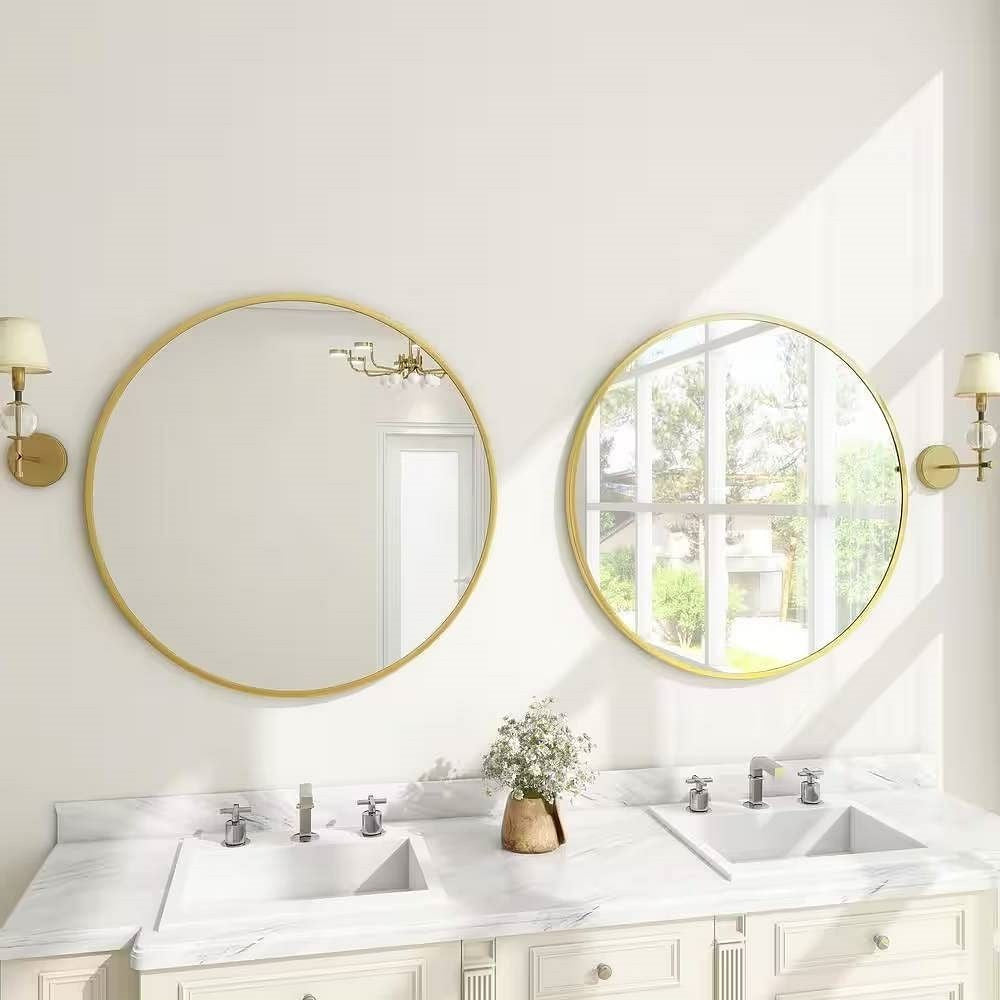 Bathroom with two round gold-framed mirrors above white sinks.