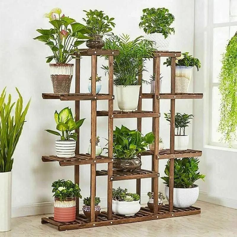 Wooden plant stand with multiple shelves holding various potted plants in a room.