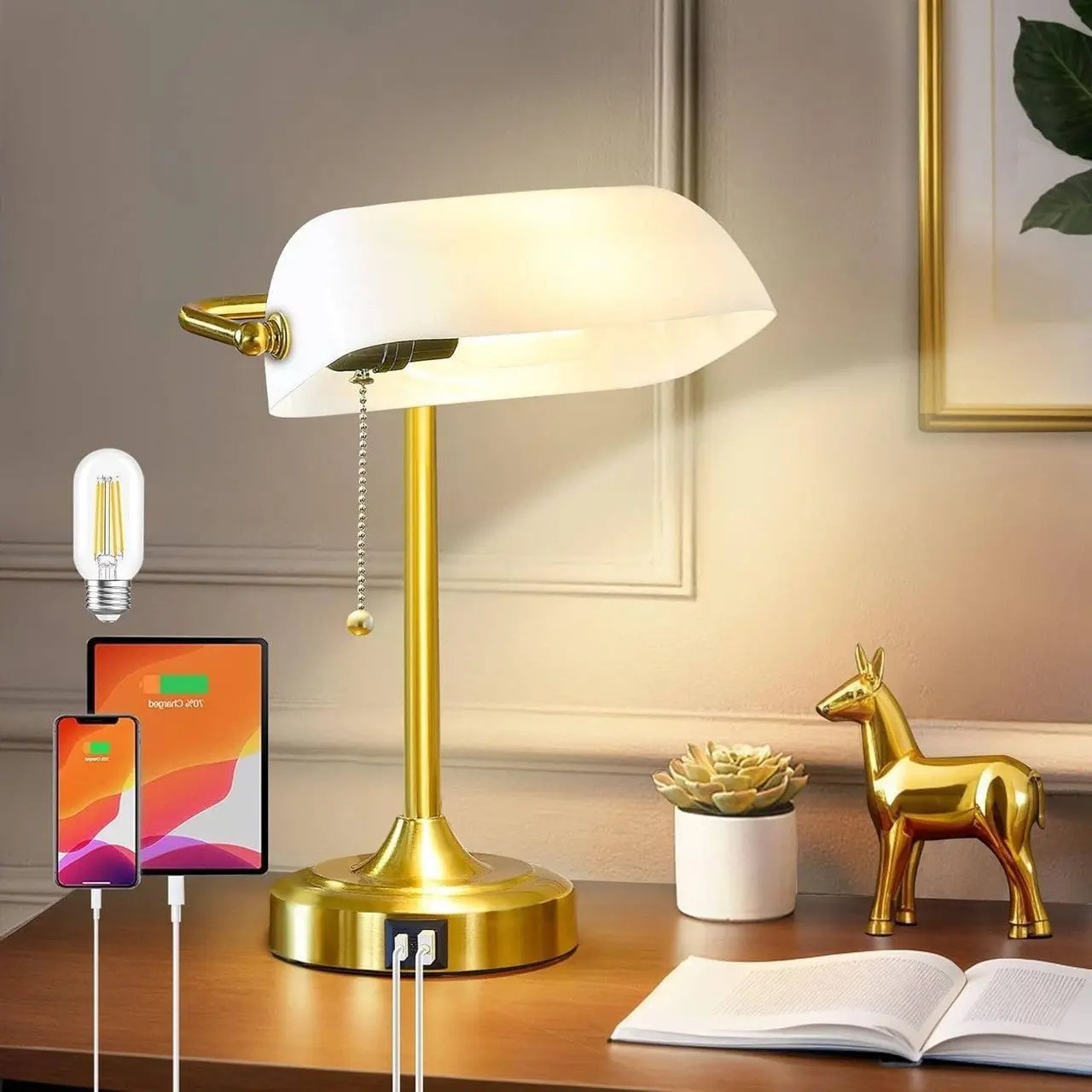 Gold desk lamp on a wooden surface with a smartphone, tablet, and charging cable in a home office setting.