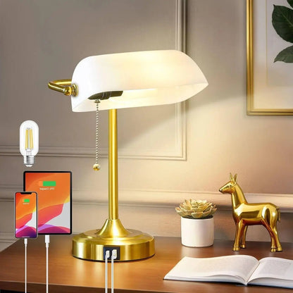 Gold desk lamp on a wooden surface with a smartphone, tablet, and charging cable in a home office setting.